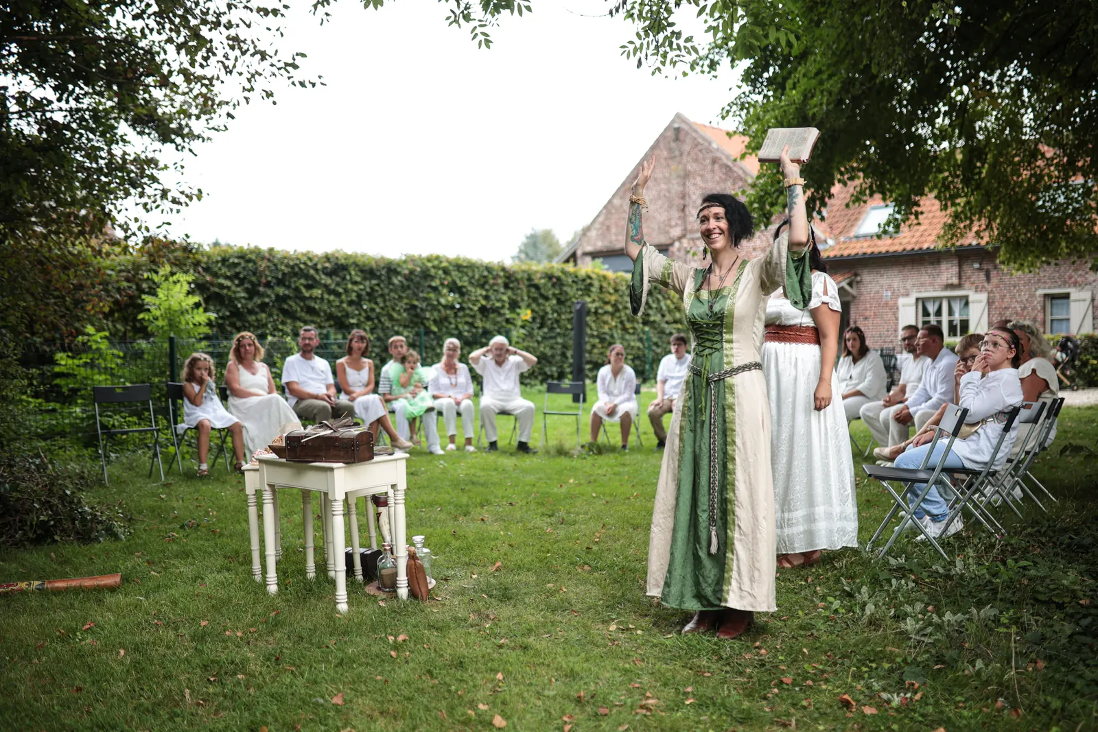Estella, officiante de cérémonie druidique, lève les bras pour ouvrir la cérémonie devant les invités