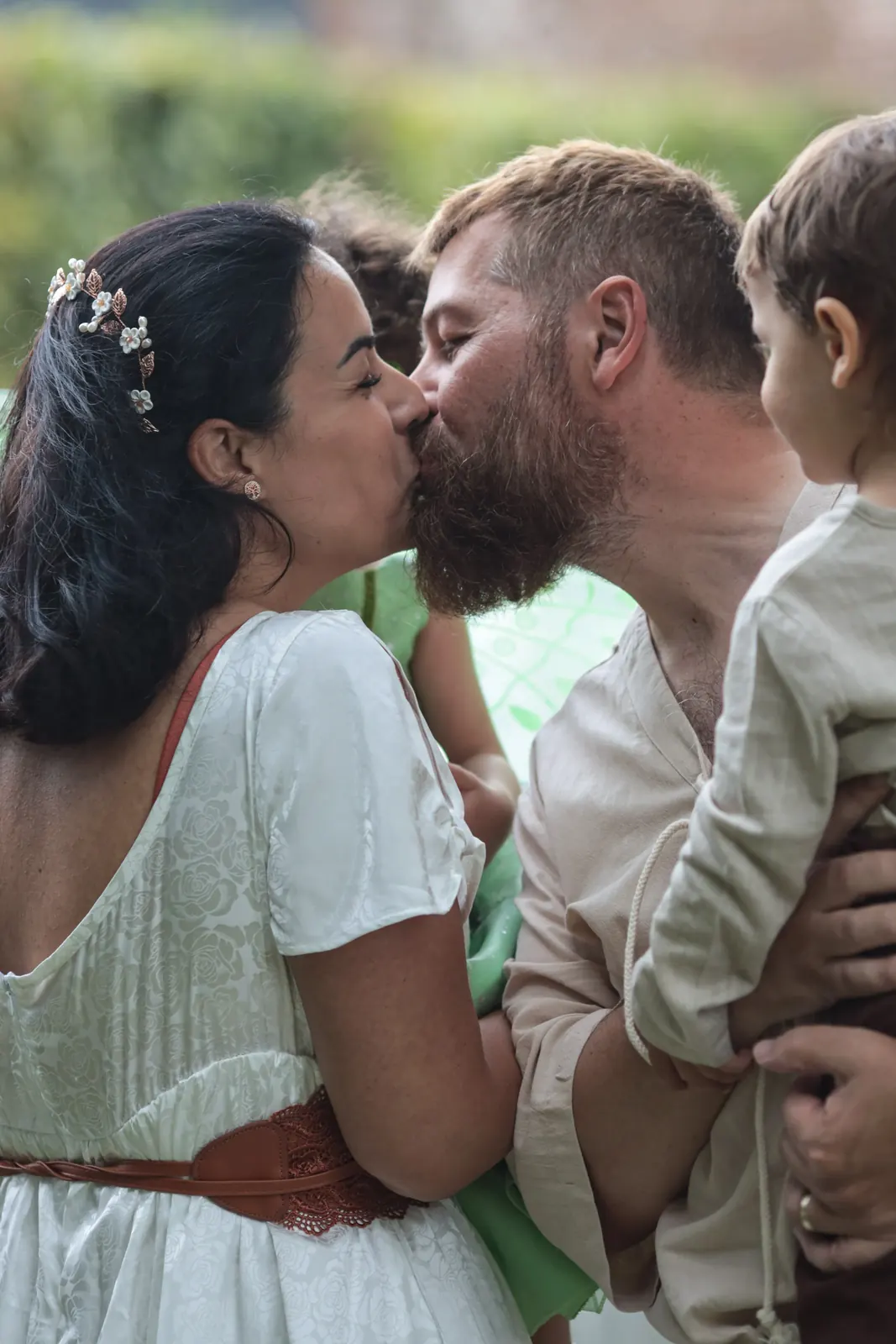Les mariés s'embrassent, leur enfant dans les bras