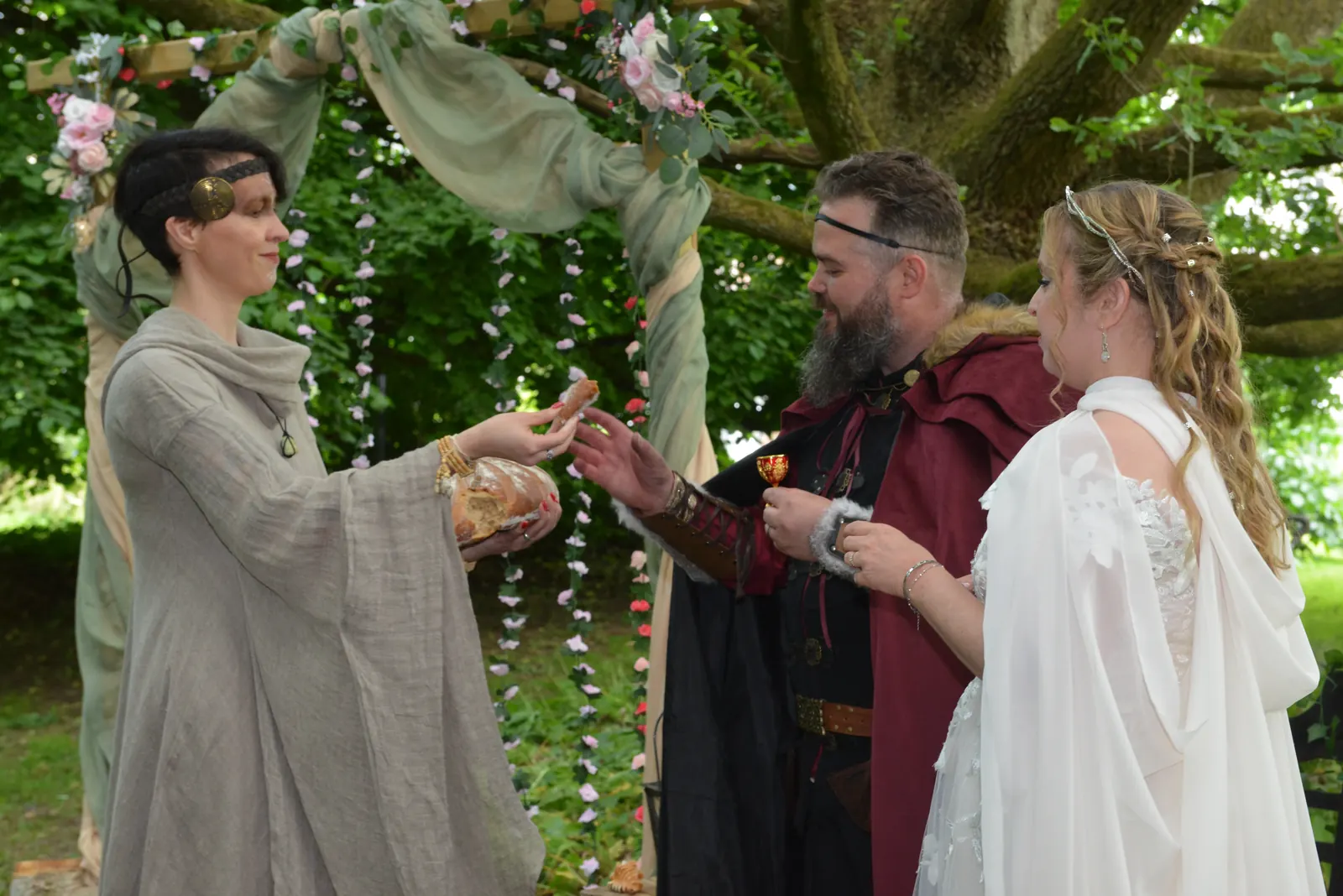 L'officiante partage un moment du rituel avec les mariés assis sous l'arbre
