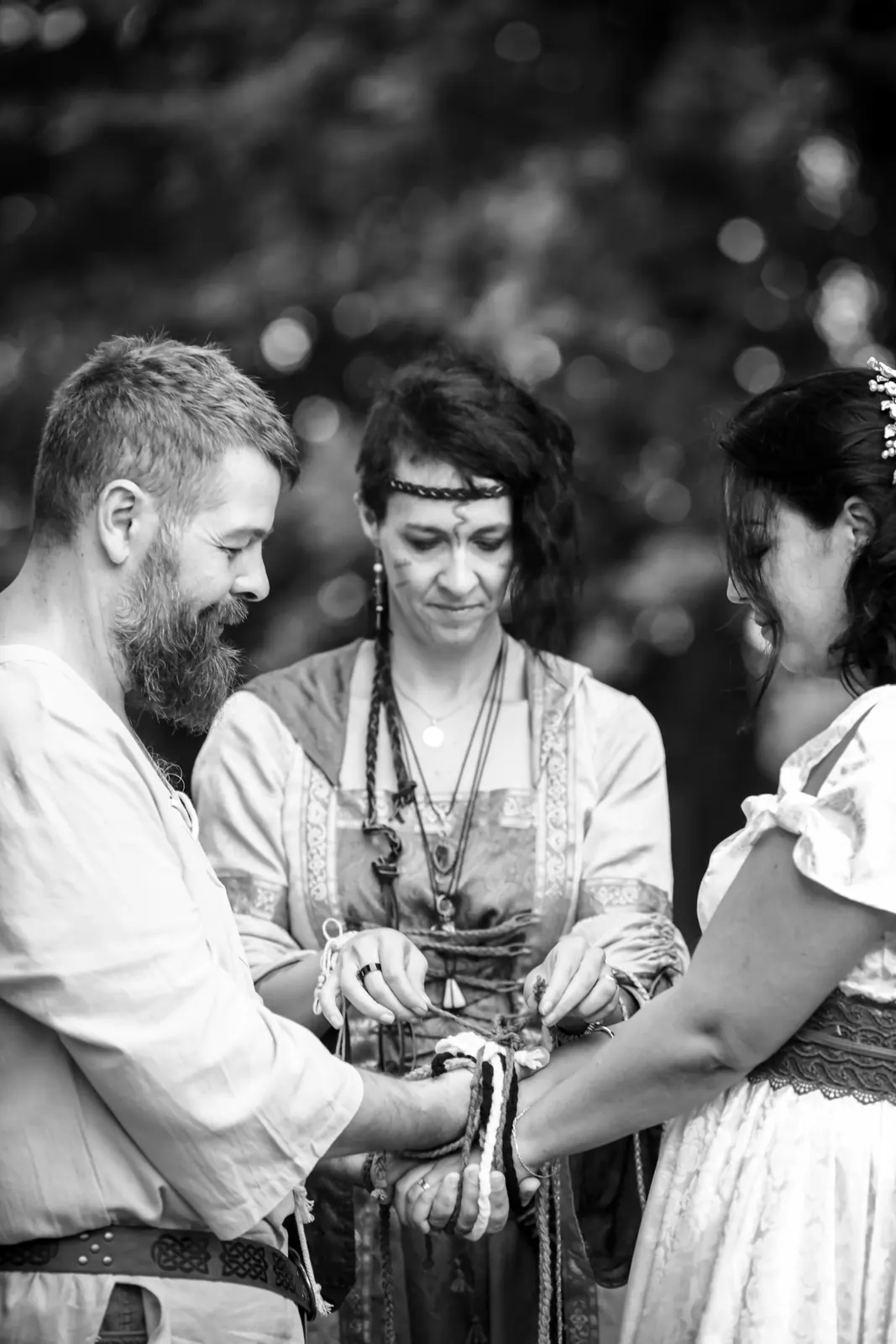 Handfasting en noir et blanc : les mains des mariés liées devant l'officiante
