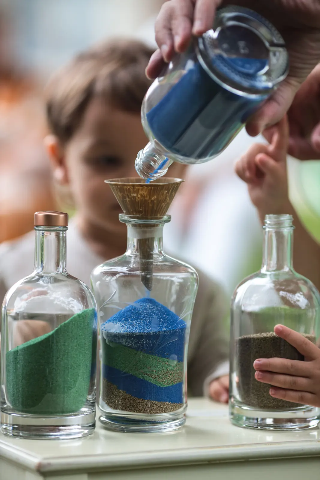 Un enfant verse du sable coloré lors du rituel du sable